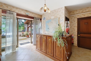 Un espace dâaccueil avec un comptoir en bois, une carte, un panneau indiquant la prĂ©sence dâune connexion Wi-Fi et une plante en pot.