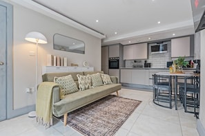 A modern living room with a sofa, a coffee table, and a dining area with chairs.
