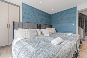 A bedroom with two beds, a wardrobe, and a blue accent wall. - Stylish | Modern 3 Bed in Holland Park - Central London (Greater London)