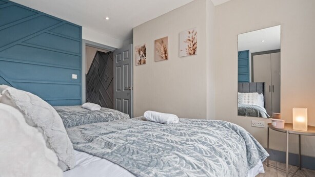 Ein Schlafzimmer mit zwei Betten, einem Schminktisch, einem Spiegel und Wandbildern.