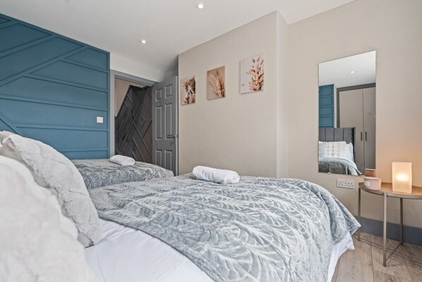 A bedroom with two beds, a dresser, a mirror, and wall art.