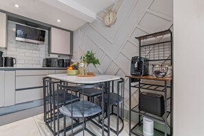 A modern kitchen with a dining area, a coffee machine, and a clock on the wall.