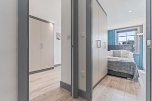 A bedroom with a bed, wardrobe, and a view of the outside.