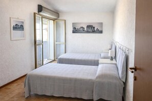Ein Schlafzimmer mit zwei Betten, einem Fenster und einem Bild an der Wand.