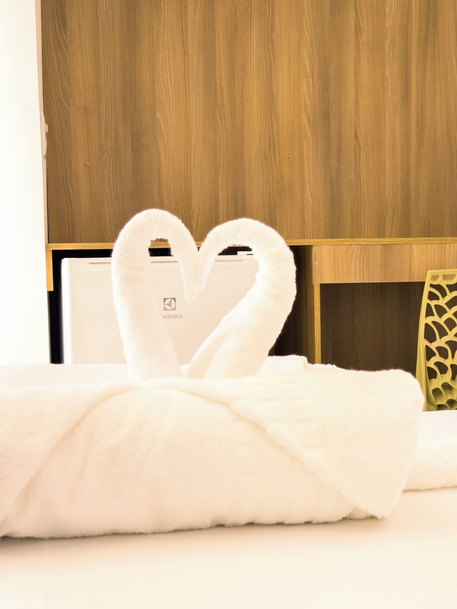 Una habitación de hotel con cama, un armario de madera y estante en la pared.