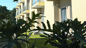 Un hotel de varios pisos con balcones, techo de tejas y un jardín bien cuidado.