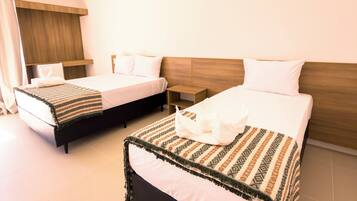 A hotel room with two beds, a wooden headboard, a bedside table, and a nightstand.