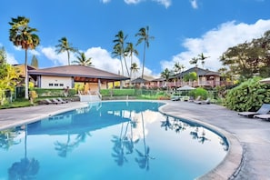A swimming pool with lounge chairs and palm trees in a resort setting. - Princeville - 5BR in 2 Condos - Sleeps 14 (Princeville)