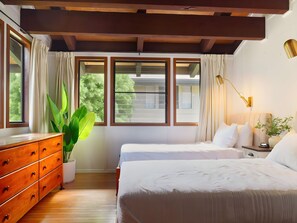 A bedroom with two beds, a dresser, a plant, and a window with curtains. - Princeville, Mauna Kai Princeville, Spacious 5 BR, Ocean View, Sleeps 14 (Princeville)