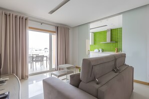 A modern living room with a sofa, a dining table, and a view of the city. - 'T1 Garden Hill' Apartment with Shared Pool, Wi-Fi, and Air Conditioning (Albufeira)