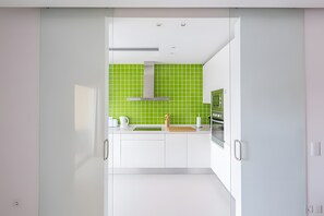 A modern kitchen with white cabinets, a green backsplash, and stainless steel appliances. - 'T1 Garden Hill' Apartment with Shared Pool, Wi-Fi, and Air Conditioning (Albufeira)