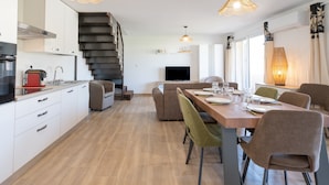A modern kitchen with a built-in oven, a dining area with a wooden table and chairs, and a staircase leading to another level. - Apartment 'La Dolce Vita 8 - Le Cedrat' with Sea View, Wi-Fi and Air Conditioning (Borgo)
