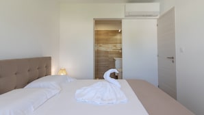 A hotel room with a bed, a bedside lamp, a door, and a view into the bathroom. - Apartment 'La Dolce Vita 8 - Le Cedrat' with Sea View, Wi-Fi and Air Conditioning (Borgo)