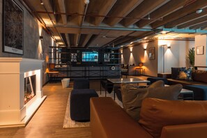 A modern interior with a fireplace, seating area, and exposed ceiling beams. - Iron Yard (Sheffield)