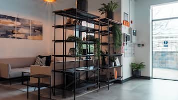 Un interior modern amb una estanteria de metall negre, un sofà i una taula de centre.