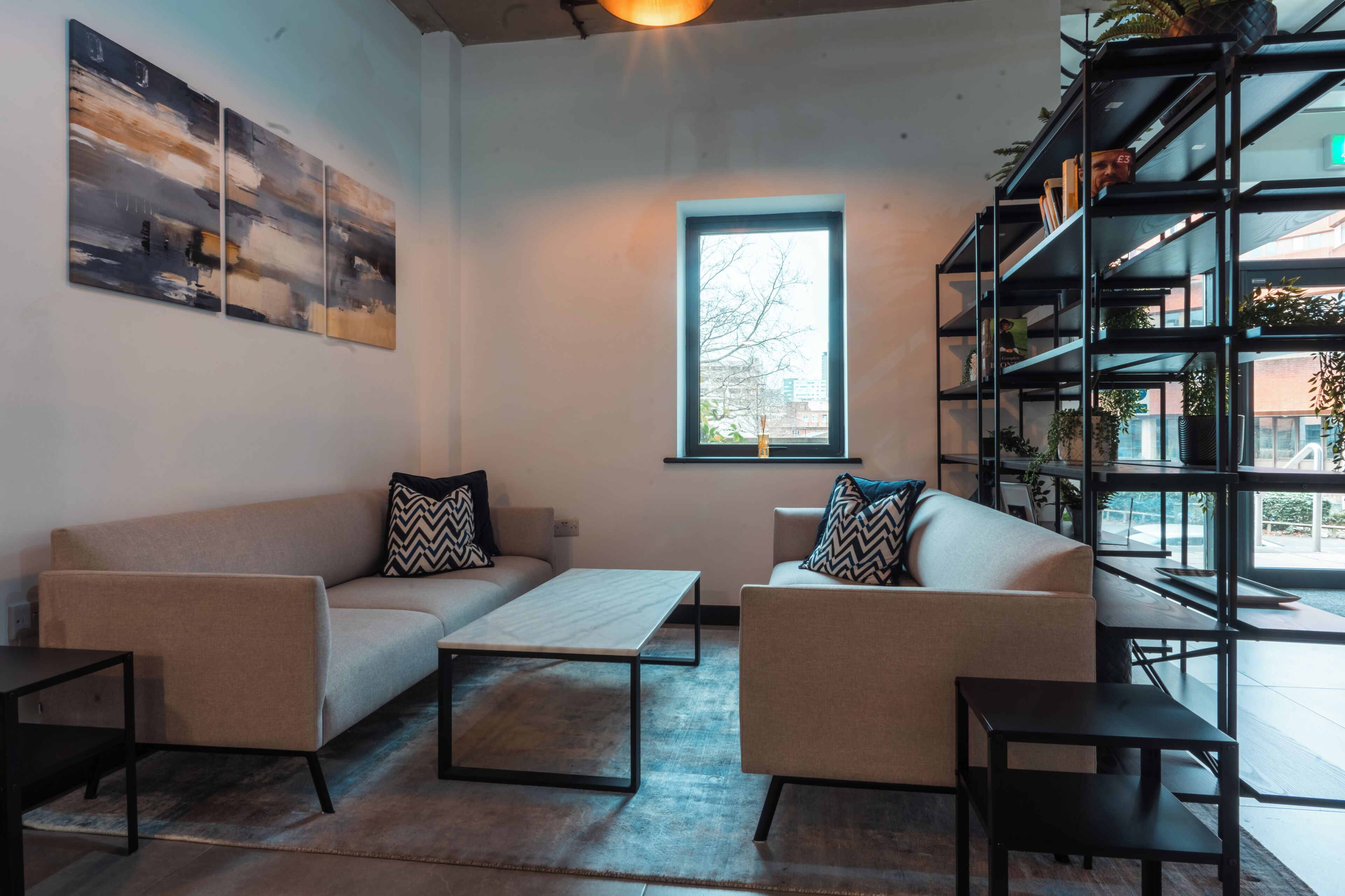 A modern living room with a sofa set, a coffee table, and a bookshelf.