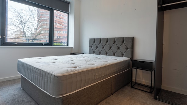 Ein Schlafzimmer mit einem großen Bett, einem Fenster und einer Tür.