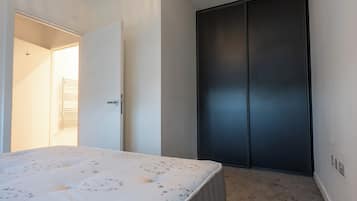 A bedroom with a bed, a wardrobe, and a door leading to another room.