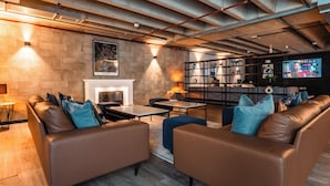 Ein modernes Wohnzimmer mit Ledersofas, einem Kamin, einem Fernseher und einem Bücherregal.