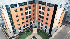 A multi-story building with a central courtyard, large windows, and a parking area. - Iron Yard (Sheffield)