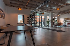 A spacious, modern interior with a long table, seating, and a bookshelf. - Iron Yard (Sheffield)
