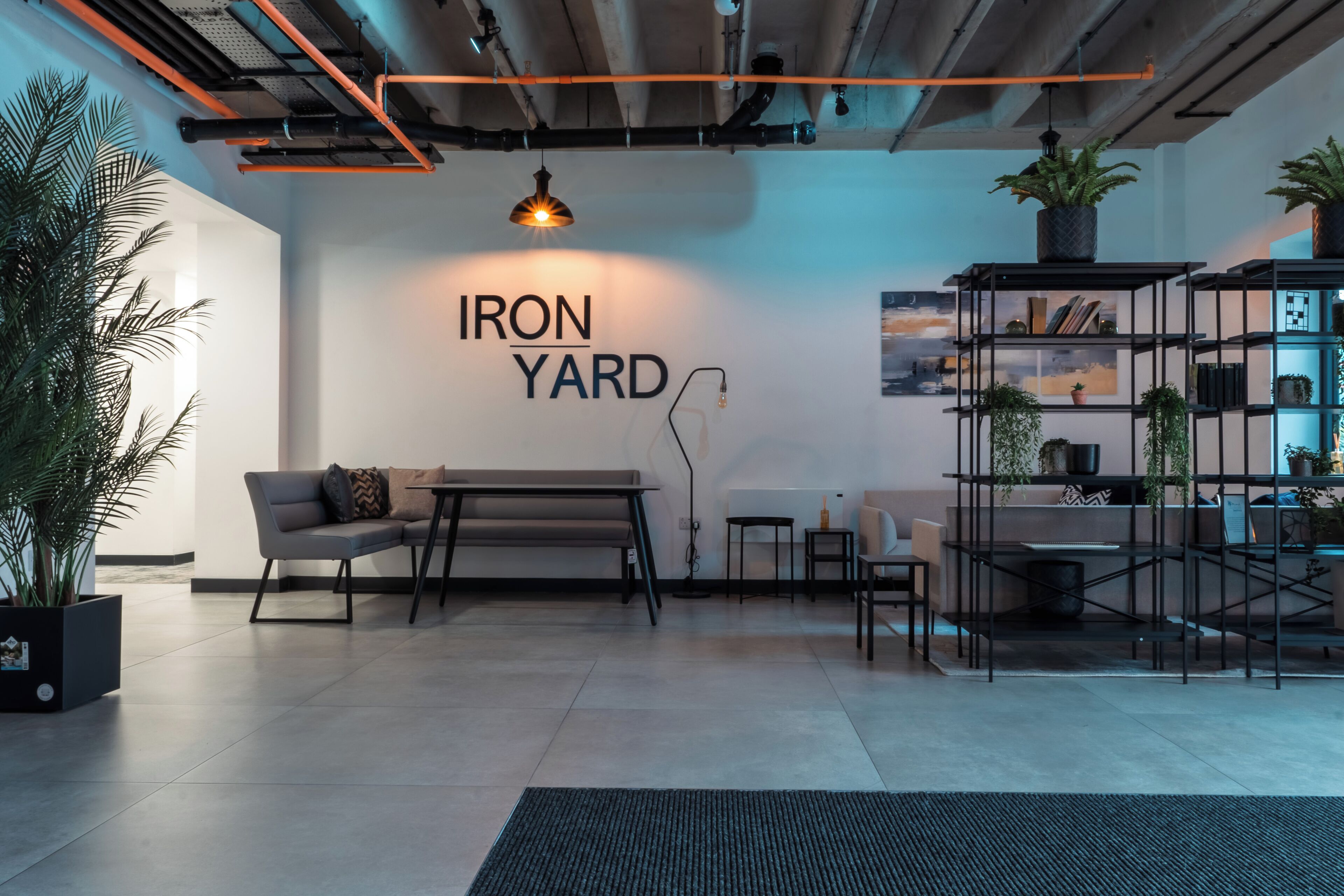 Un interior moderno con un sofá, una mesa, una estantería y un cartel en la pared que dice 'IRON YARD'.