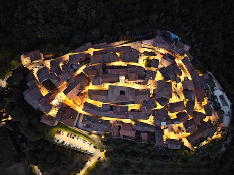 An aerial view of a historic walled town with a central square, narrow streets, and a parking area.. La Casa Di Memmo in the Heart of the Sienese Countryside