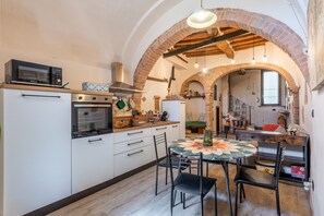 A kitchen with an oven, microwave, and a dining area with a table and chairs.