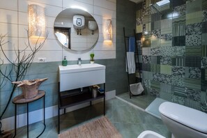 A bathroom with a white sink, mirror, and a patterned wall. - Villa Ninfea - Capri Garden Retreat (Capri)