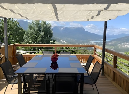 A deck with a table and chairs, a view of mountains, and a wooden railing.. Guest Room “Écureuil - Camping Le Mont Orel” with Lake View and Shared Terrace