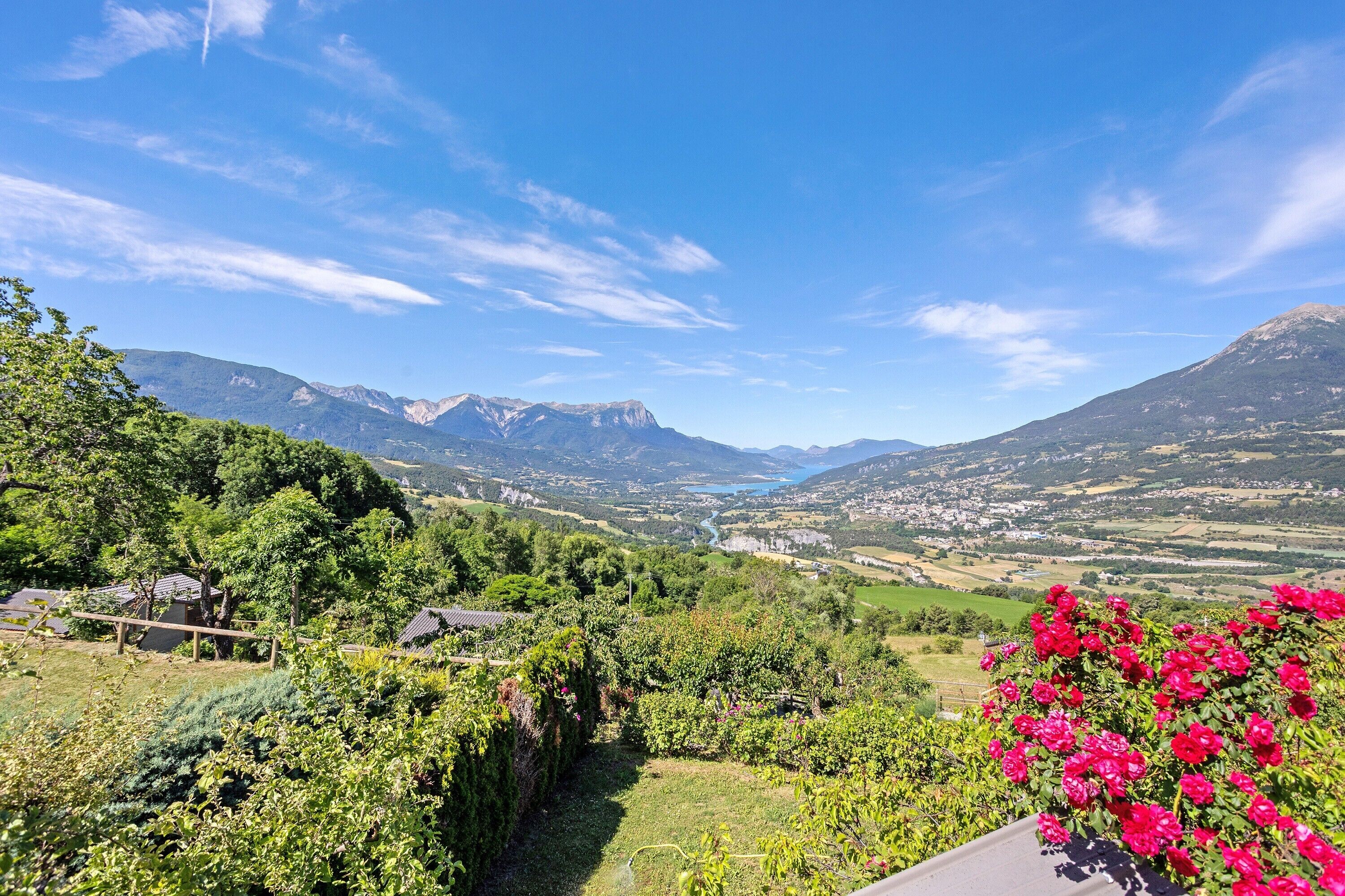 A mountainous landscape with a valley, a river, and a clear sky.