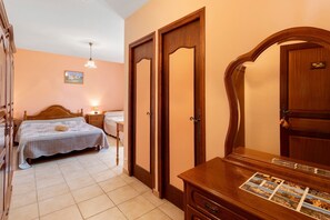 Une chambre Ă coucher avec un lit, une commode, un miroir et une porte.