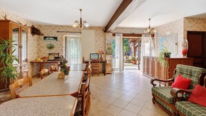 A spacious living area with a dining table, chairs, a sofa, and a fireplace. - Primevère Guest Room with Shared Terrace, Garden & Wi-Fi (Milhac)