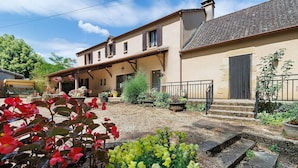 A two-story house with a garden, a front porch, and a staircase leading to the entrance. - Primevère Guest Room with Shared Terrace, Garden & Wi-Fi (Milhac)