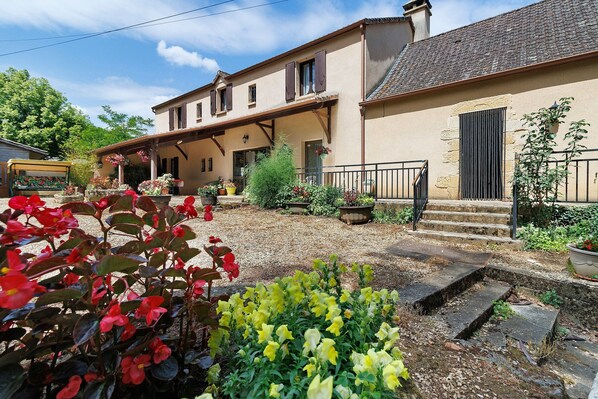 Ein zweigeschossiges Haus mit Garten, einer Veranda und einer Treppe, die zum Eingang fĂŒhrt.