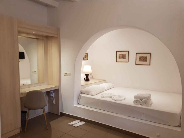 Una habitación con una cama, un escritorio, una silla, una lámpara y dos cuadros en la pared.