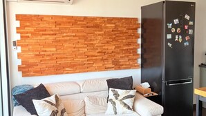 Ein modernes Wohnzimmer mit einem weißen Sofa, einem schwarzen Kühlschrank und einer Holzvertäfelung.