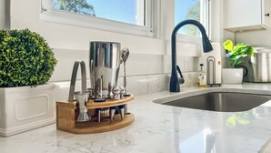 Cucina con piano di lavoro in marmo, lavello, rubinetto blu e una pianta in vaso.