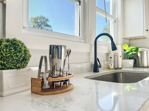 A kitchen with a marble countertop, a sink, a potted plant, and a decorative metal container.