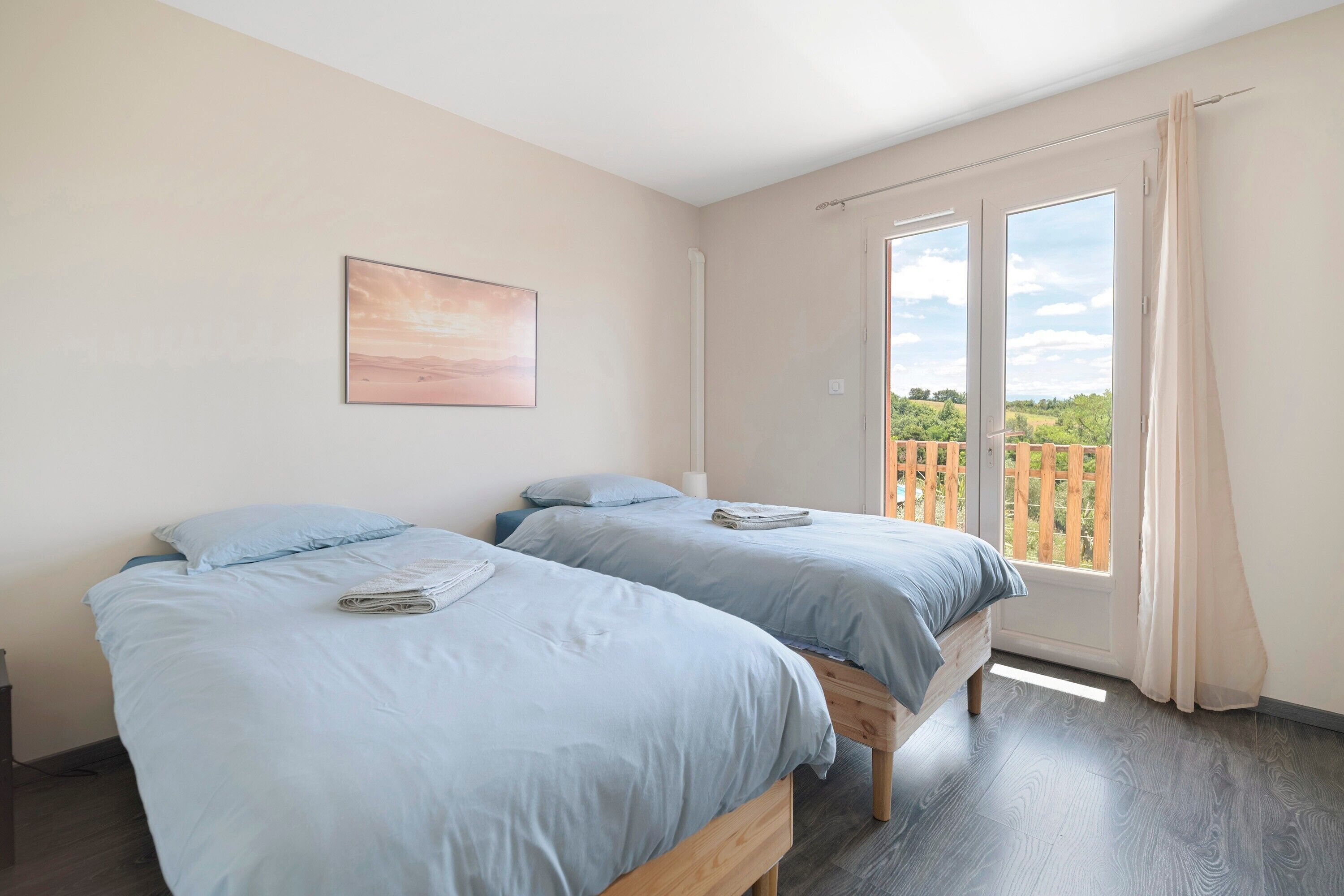 Une chambre avec deux lits, une fenêtre avec des rideaux et un tableau au mur.