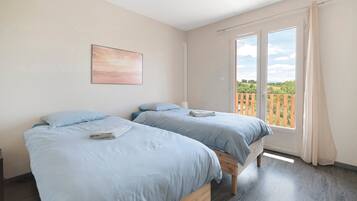 Une chambre avec deux lits, une fenêtre avec des rideaux et un tableau au mur.