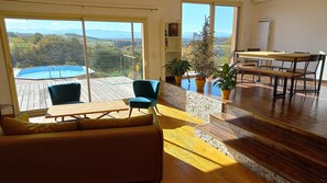 En rummelig stue med træterrasse, pool og bjergudsigt.