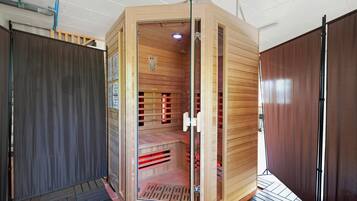 A sauna with a glass door, wooden interior, and a control panel.