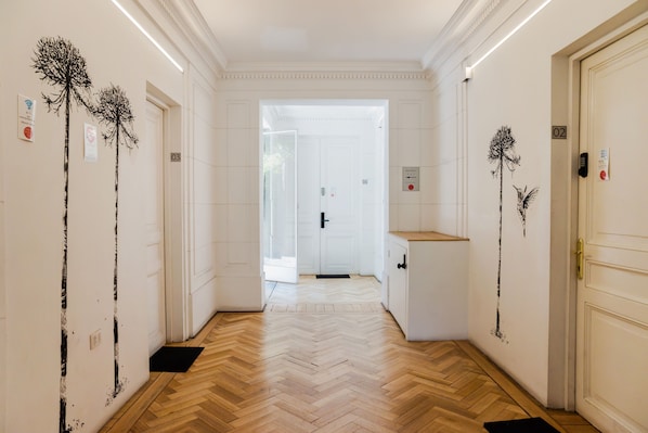 A hallway with white walls, wooden herringbone flooring, and doors numbered 02 and 03. - Terranova Apartments by Andes STR (Providencia)