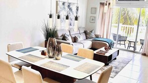 A modern living room with a dining area, featuring a sofa set, a coffee table, and hanging pendant lights. - Isabela Jardin • Cozy Luxe Stay • 3BR • Pool + AC (Isabela)
