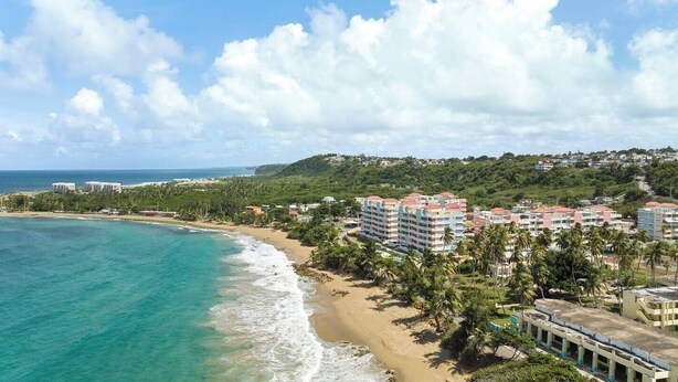 A coastal area with a beach, ocean, and buildings with red roofs. - Isabela Jardin • Cozy Luxe Stay • 3BR • Pool + AC (Isabela)