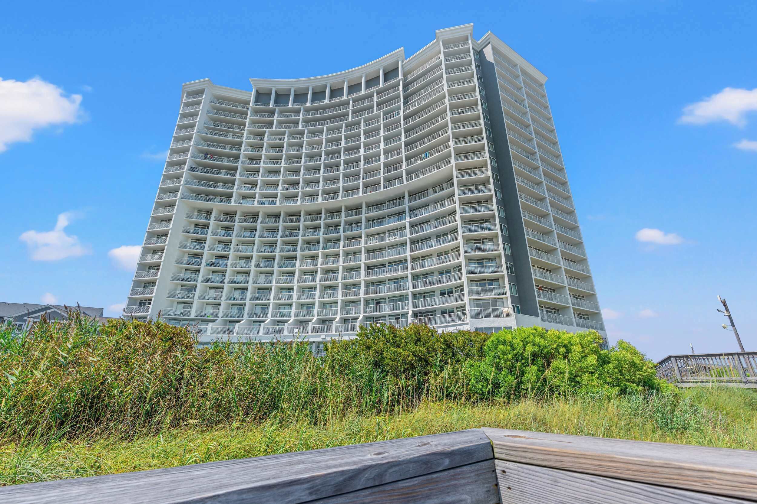 Un hôtel de grande hauteur doté de nombreux balcons, d’une architecture aux lignes courbes et offrant une vue sur la verdure environnante.