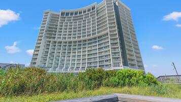 Un hôtel de grande hauteur doté de nombreux balcons, d’une architecture aux lignes courbes et offrant une vue sur la verdure environnante.