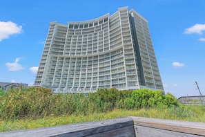 A high-rise hotel with multiple balconies, a curved architectural design, and a view of the surrounding greenery. - SeaWatch 414 Ocean View (Myrtle Beach)