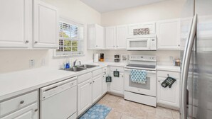 A kitchen with white cabinets, a microwave, an oven, a dishwasher, and a refrigerator. - "Seas the Day" at barefoot resort in Ironwood (North Myrtle Beach)